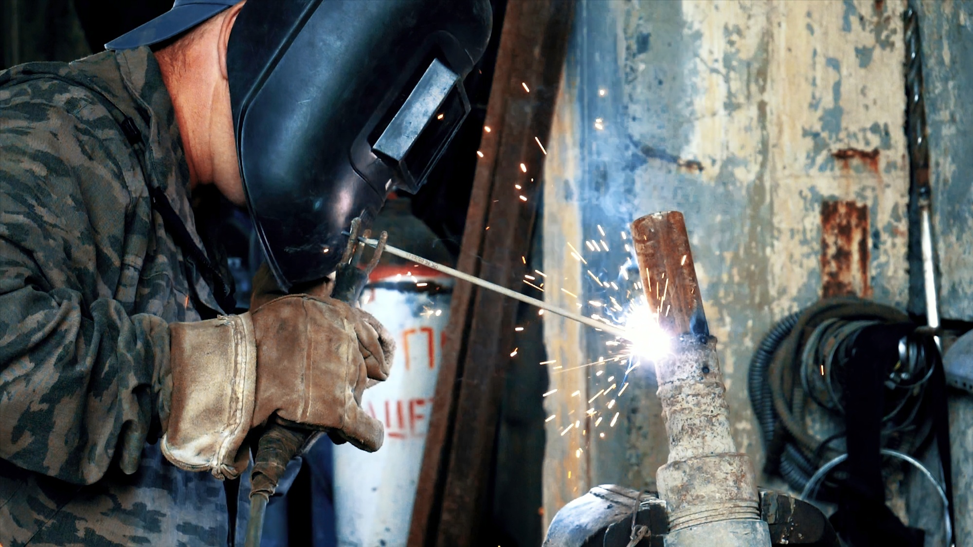 Welder at the factory in welding mask welds metal parts. Frame. Masked welder welding parts. Welding