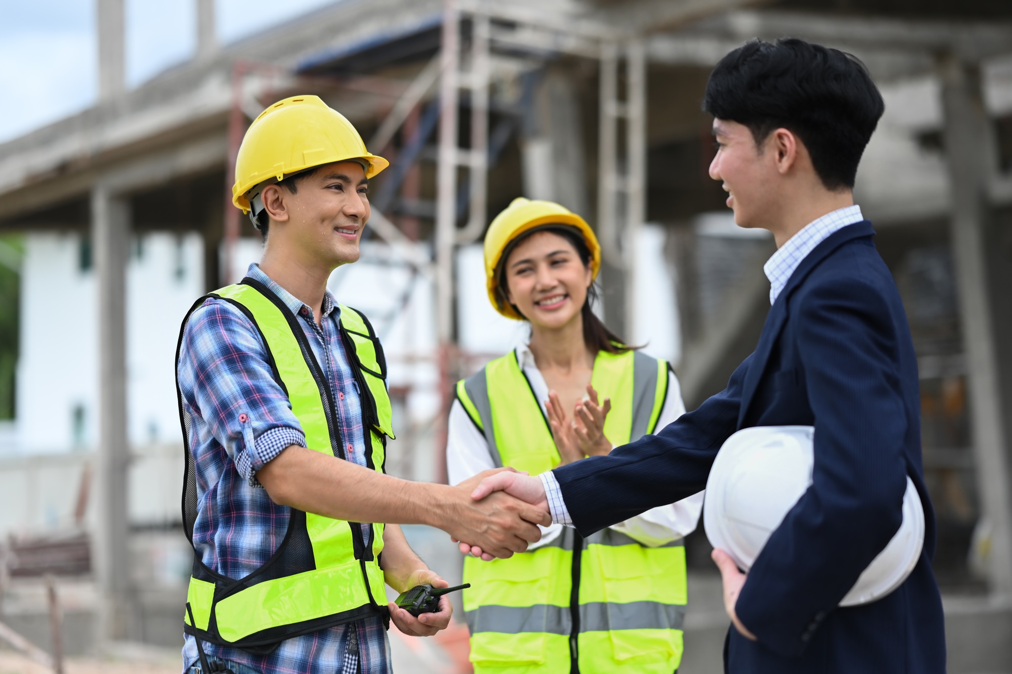 Construction manager shaking hands with investor at building site.